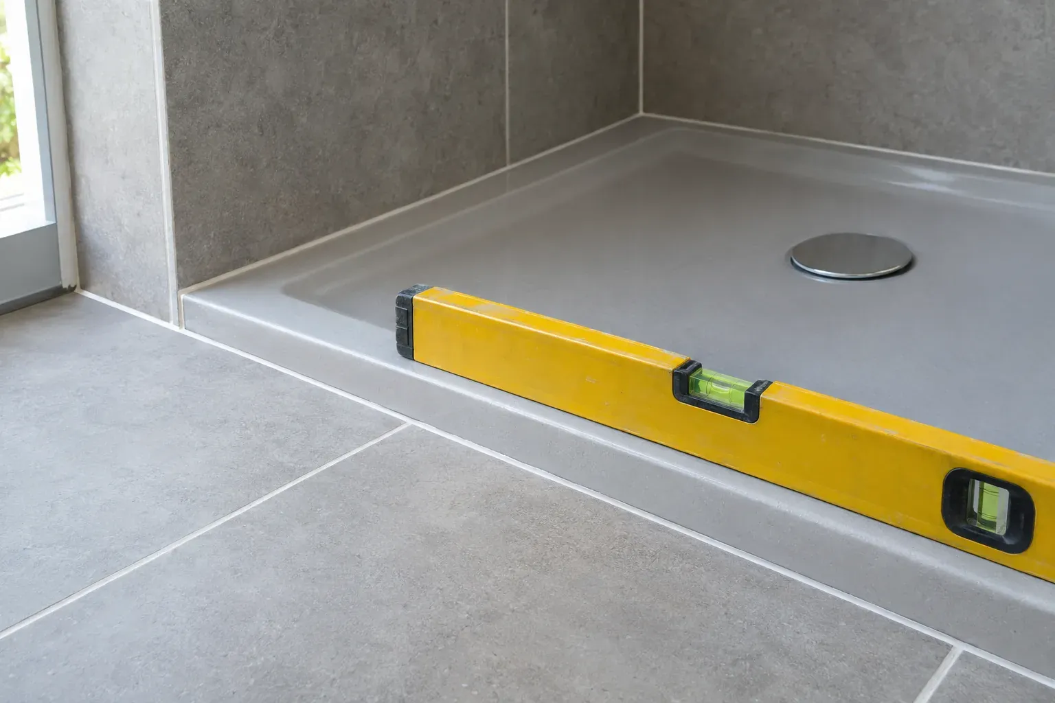 Base de duche nova em cinzento, com um nível de bolha pousado na borda